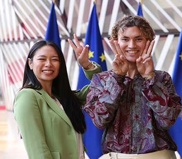 Giovani sorridenti con dietro bandiere Unione Europea