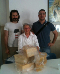 Foto dei due artisti dello spettacolo, di un'addetta e del parmigiano consegnato alla mensa dei poveri