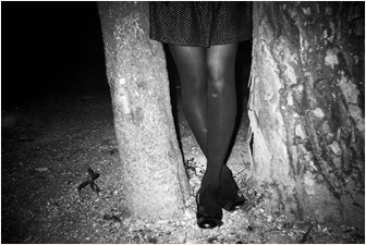 Foto in bianco e nero della parte inferiore di busto di donna vicino ad albero.
