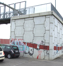 Foto del muro del pilone del ponte pedonale che si affaccia sul parcheggio