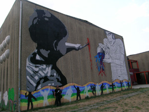 murales intero di un bambno che dipinge con un pennello e un uomo che versa un barattolo di vernice colorata