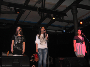 Foto di tre ragazze sul palco durante l'esibizione