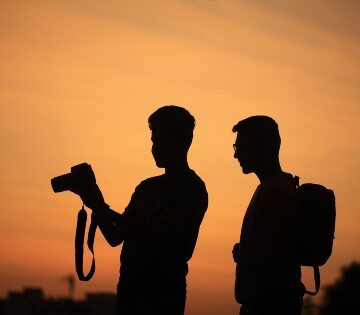 sagoma di 2 ragazzi che fotografano il tramonto