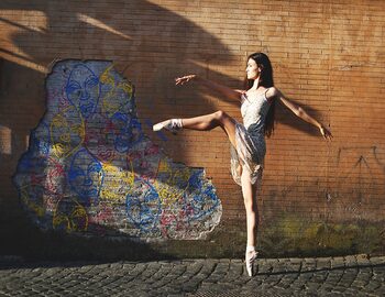 Una ballerina protende la sua gamba verso un muro dove spuntano fuori le opere a stencil di gesta future