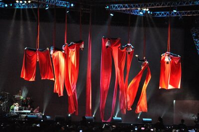 Foto di artisti-acrobati sul palco appesi a tessuti aerei di colore rosso durante uno spettacolo