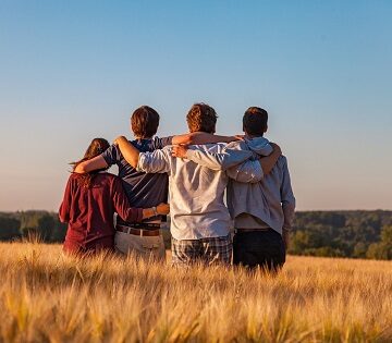 Giovani abbracciati di spalle in un campo