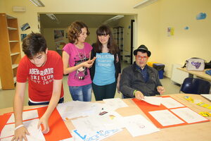 Tre ragazzi del laboratorio di fumetto con il loro tutor Niccolò Storai preparano i disegni per la mostra