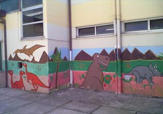 Foto di murales a colori raffigurante dinosauri su edificio scolastico