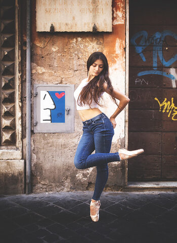Una ballerina in jeans davanti al poster di k2m artista sardo con base a Roma
