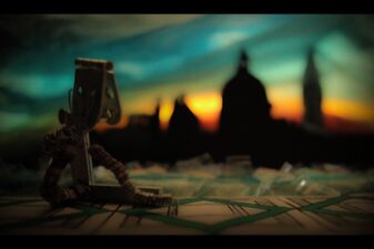 Fotogramma a colori di pupazzo robot seduto e sullo sfondo una città al tramonto